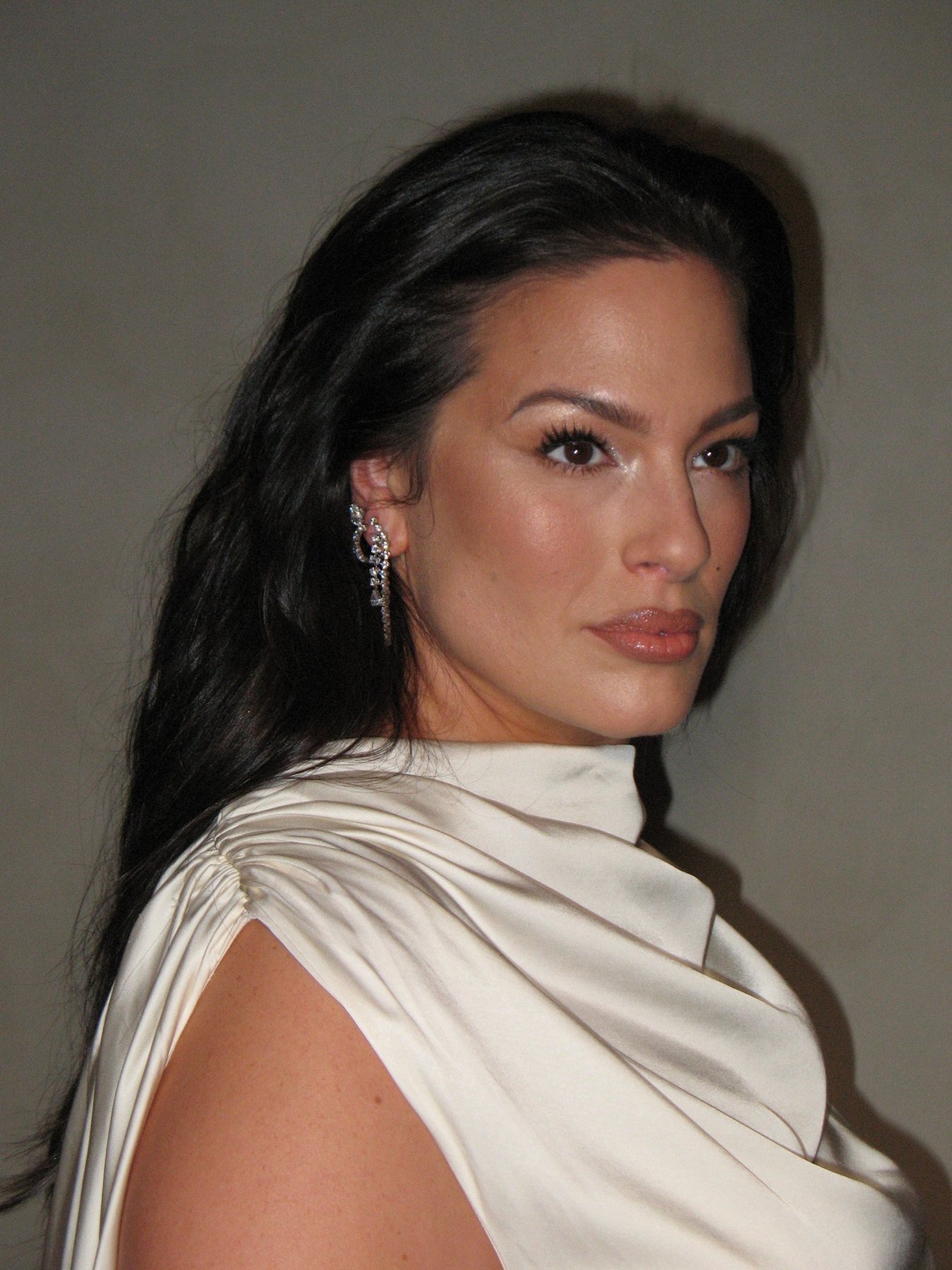 Ashley Graham in profile, long glossy waves swept back over one shoulder