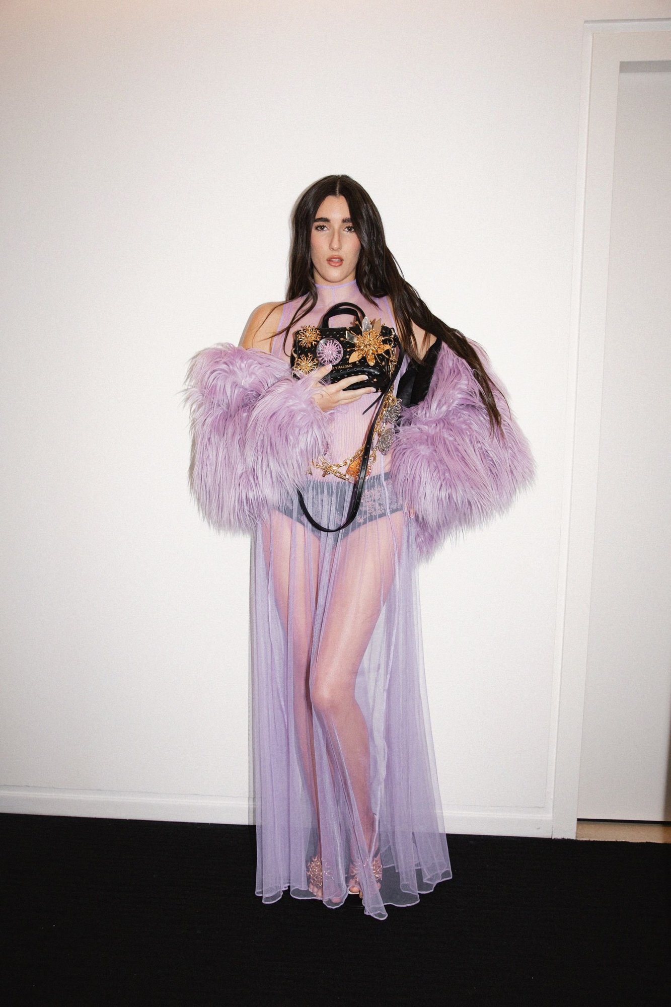 Judeline full-length against a white wall in sheer lilac tulle and faux fur, long dark hair