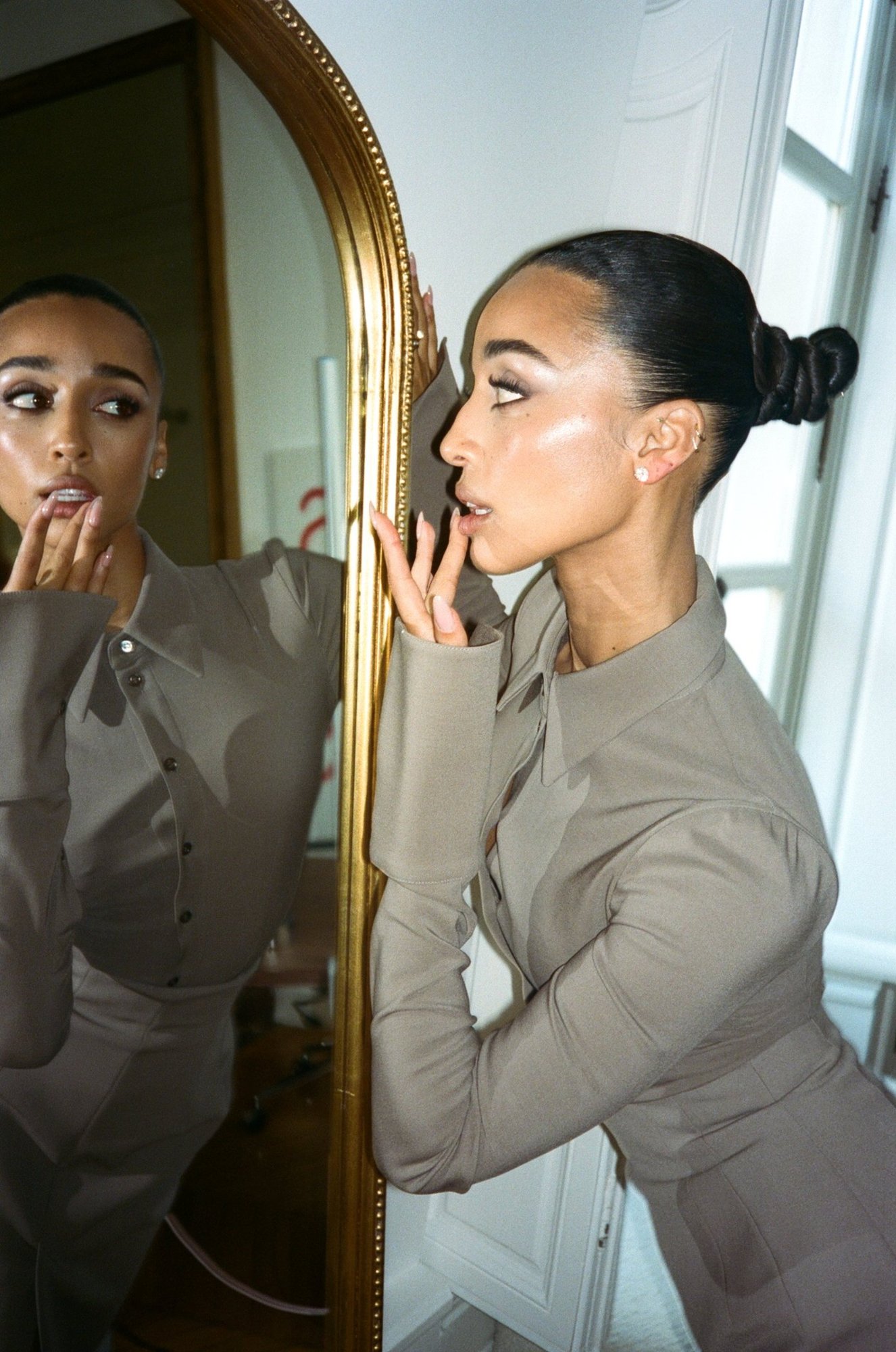Eloise Dufka at a gilded mirror, profile of her sleek coiled bun