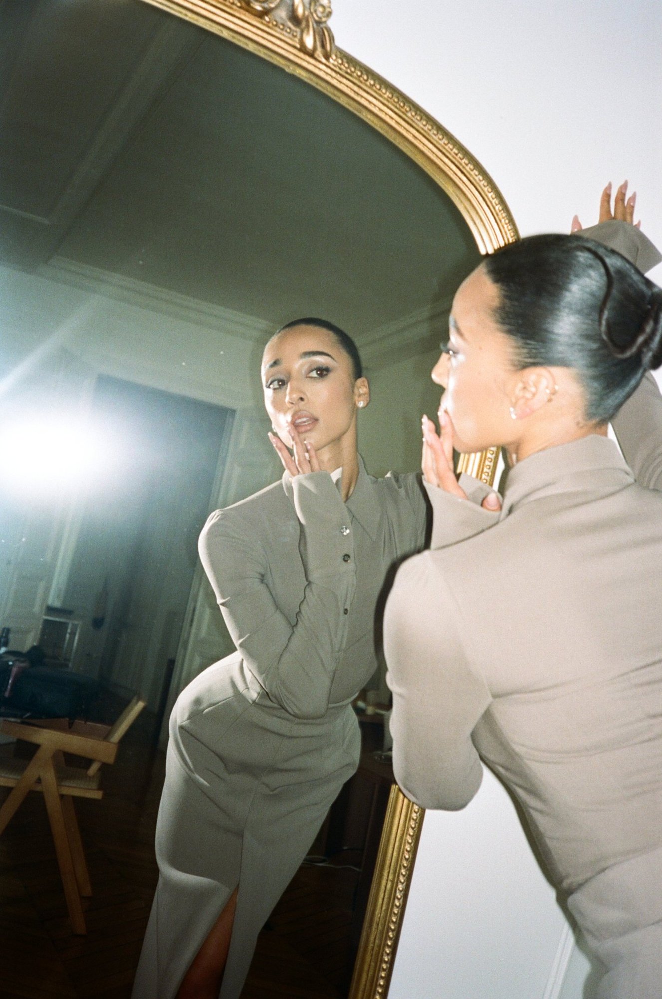 Eloise Dufka reflected in a gilded mirror, the coiled bun seen from behind