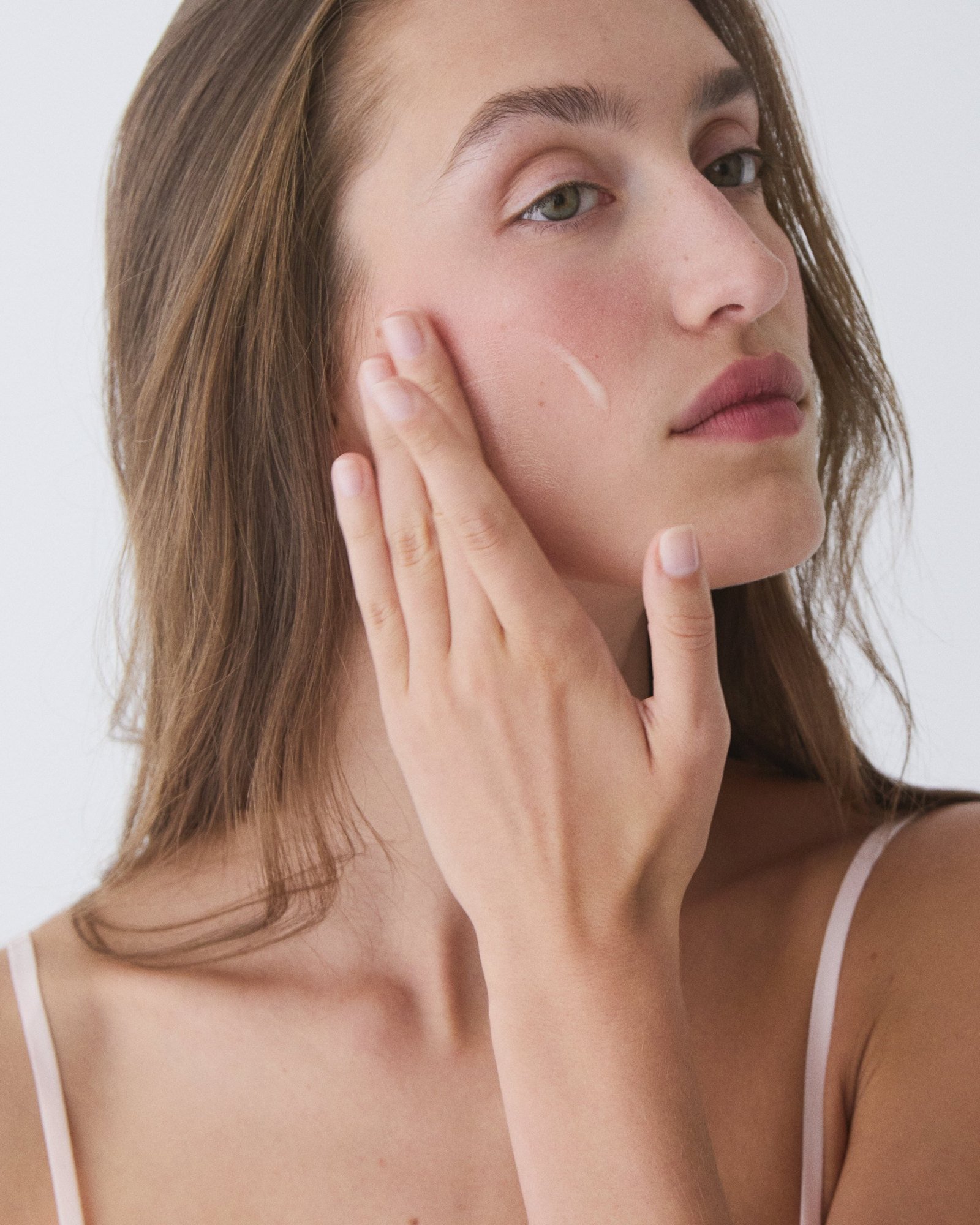 Hand to cheek applying serum, sleek tucked lengths