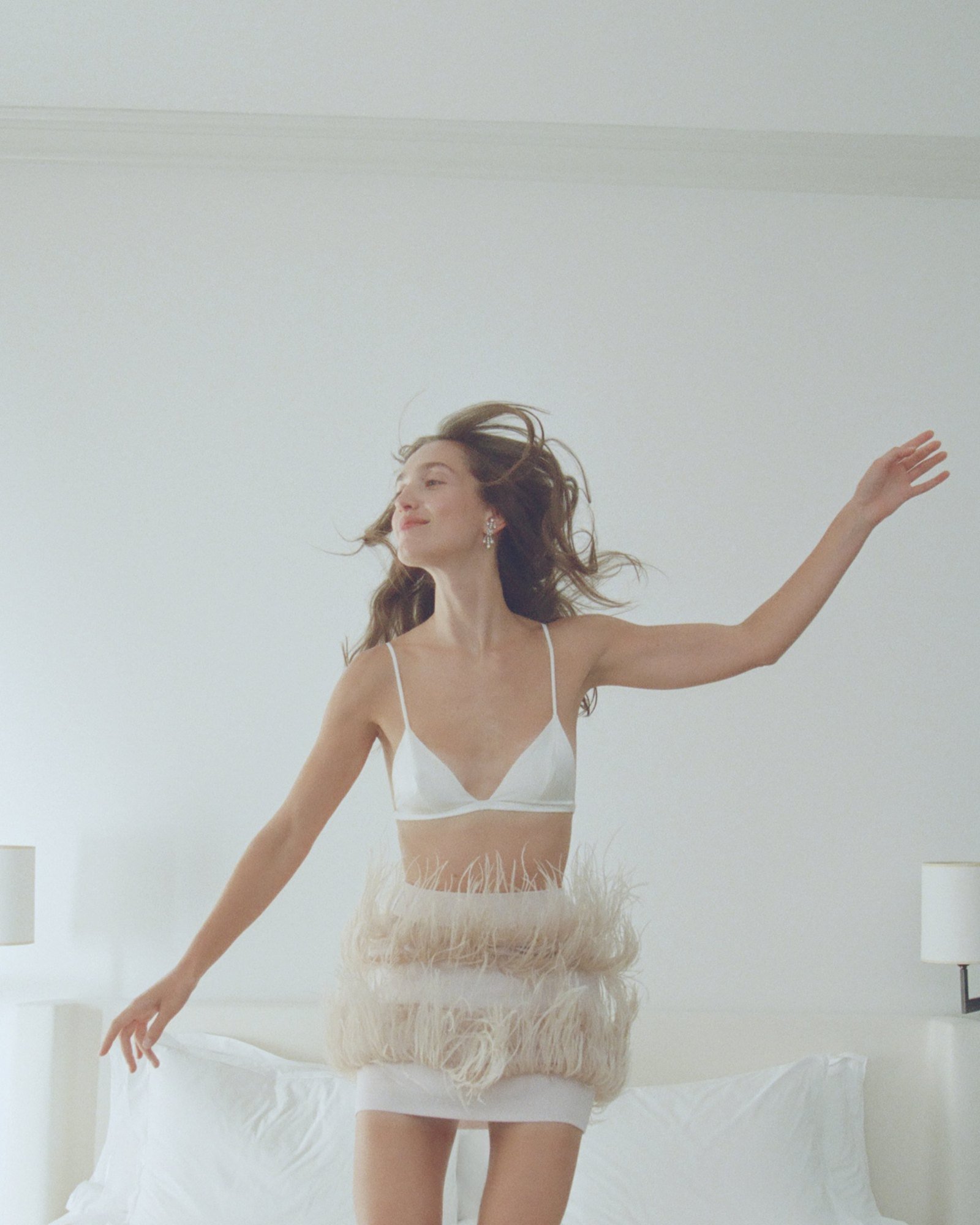 Dancing in a white bra and feather skirt, long hair in motion