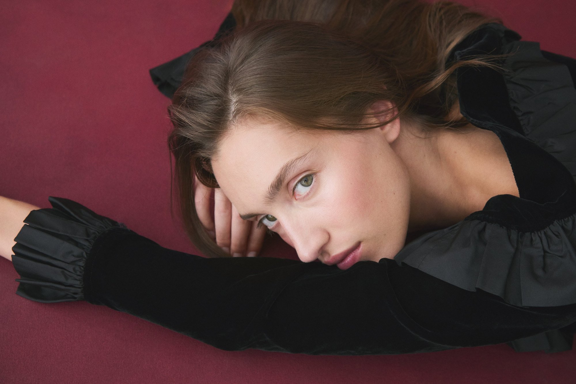 Lying on burgundy with a soft side-swept fringe and loose updo