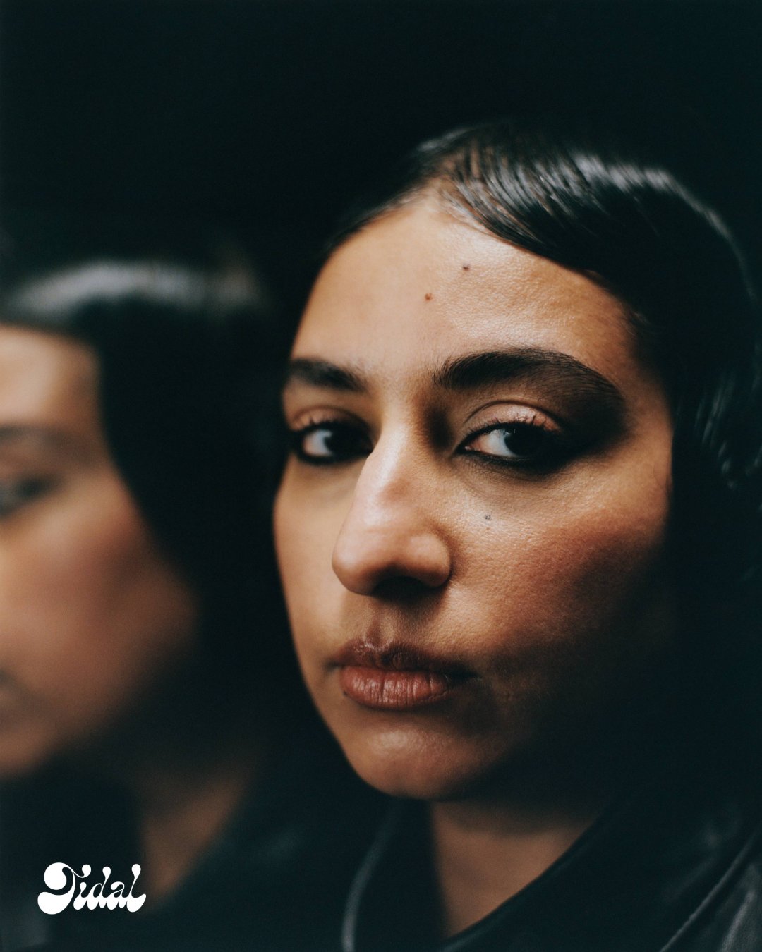Close-up of Arooj Aftab with sleek, sculpted hair and a reflection beside her