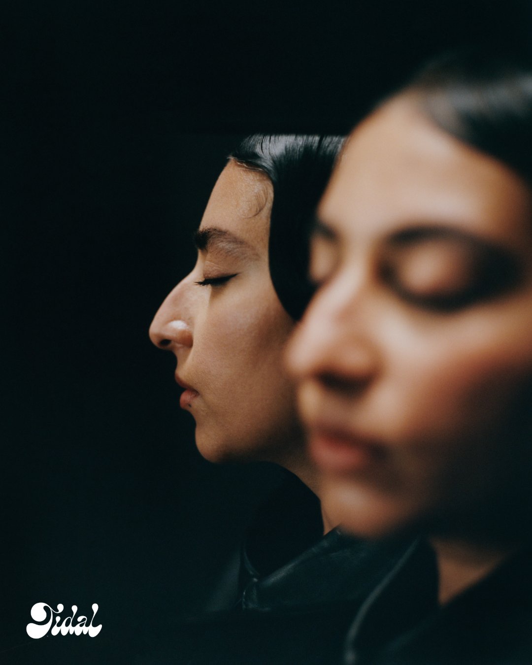 Double profile of Arooj Aftab with eyes closed, sleek hair in soft focus